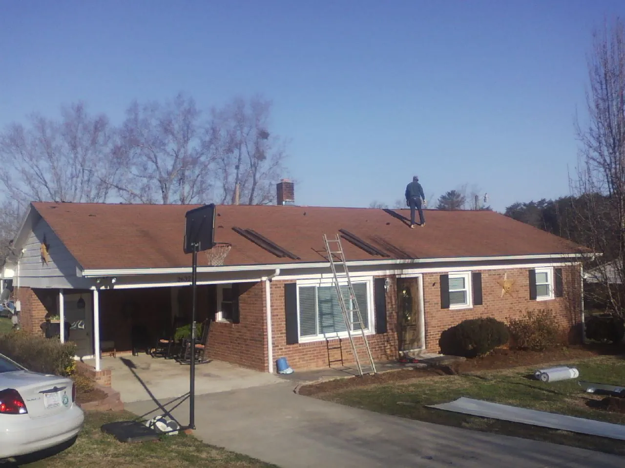 Roofer stripping a shingle roof on a brick ranch before metal panels in West Springfield