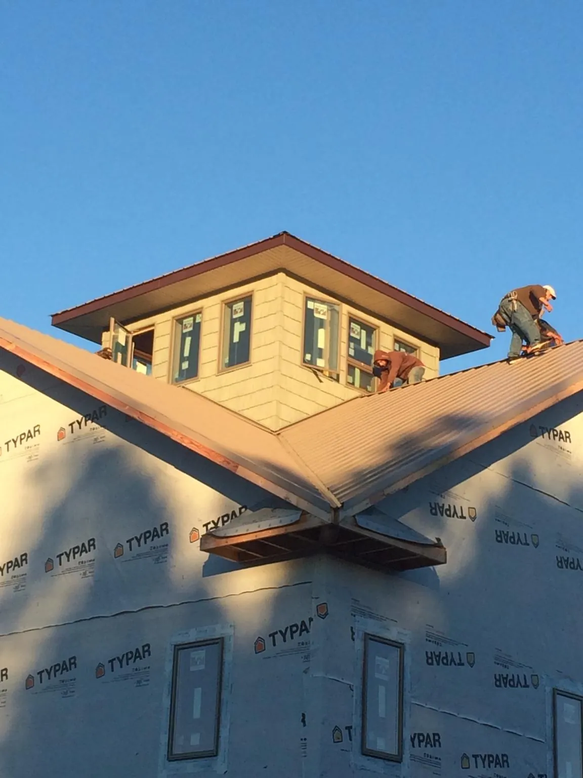 Roofers working around a rooftop cupola on a new metal roof at sunset — Roof Waterproofing in West Springfield by Roofing Brothers